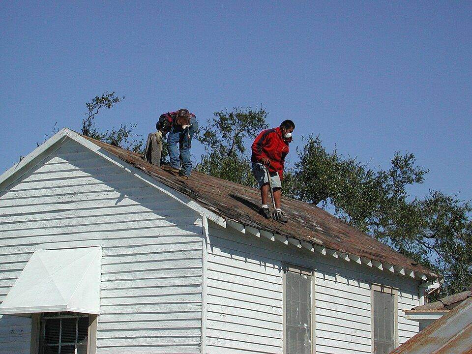 Roofers replacing shingles on a house